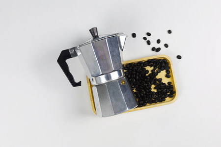 Moka pot with coffee beans and wooden tray on white backgroundの写真素材