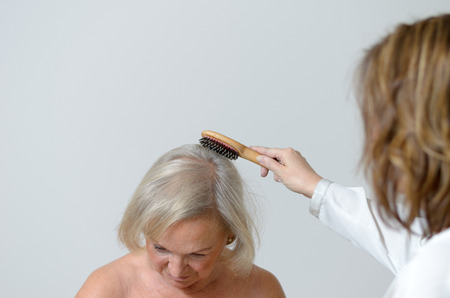 Elderly lady gets her hair combed maybe she lives in a home for old people and care needsの写真素材