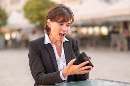Horrified woman unable to pay her bill at a street cafeteria as she realises that her wallet is empty and she does not have her credit cardの写真素材