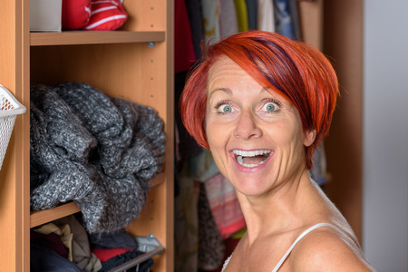 Surprised Middle Aged Redhead Woman in front of her wardrobeの写真素材