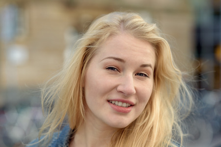 portrait of young blond beautiful woman with blue eyes smiling to the cameraの写真素材