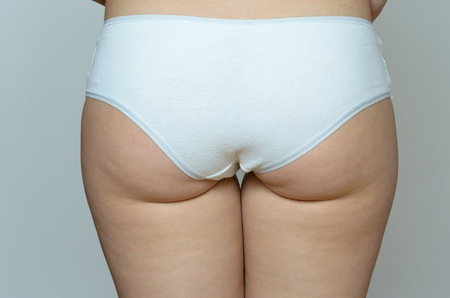 Close up Butt of a Young Woman Wearing White Underwear Against Gray Background.