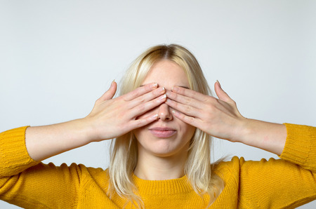 Close up Young Woman Covering her Eyes with Bare Hands Against Gray Background.の写真素材