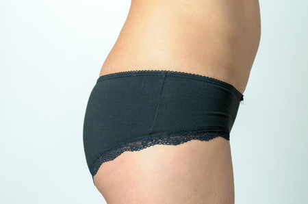 Close up Butt of a Middle aged Woman Wearing Black Underwear Against Gray Background.