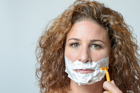 Close up Serious Face of a Blond middleaged Woman shaving her beard, Staring at the Cameraの写真素材