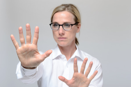 Businesswoman standing against grey background and using Hands on security system to get accessの写真素材