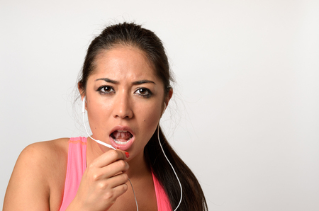 Attractive young woman having a telephone call with her earplugs with a smile looking at the camera in a head and shoulders viewの写真素材