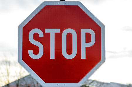 Close up of red and white stop sign in front of obscure building outdoorsの写真素材