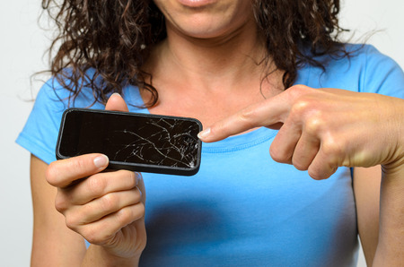 Close up of one woman in blue shirt holding broken mobile phone in her handsの写真素材
