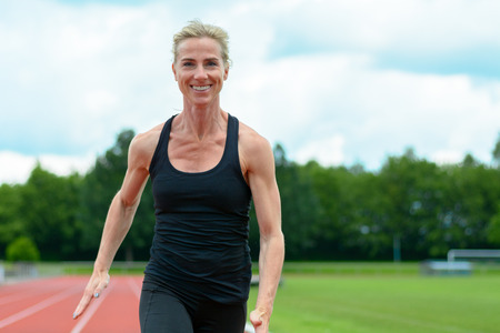 Healthy fit young woman running on a sports track at a stadium as she enjoys her daily workout in a health and fitness conceptの写真素材