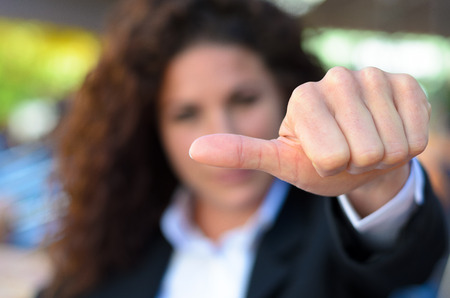Woman abstaining from voting holding her thumb to the side to show her uncertainty, disinterest or...