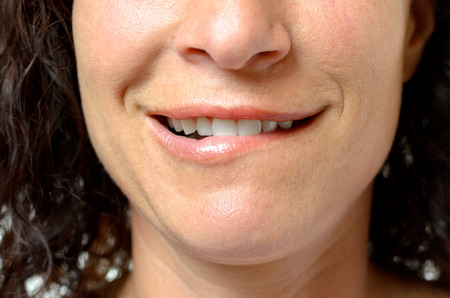 Thoughtful or seductive young woman biting her lip with a smile and sensual expression, close up of...