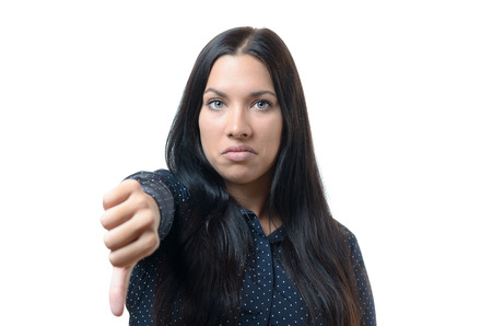 Rebellious negative woman giving a thumb down gesture with a frown to show her displeasure and register a no voteの写真素材