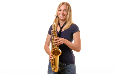 Attractive young blond woman saxophonist in jeans with a treble saxophone, three quarter view isolated on whiteの写真素材