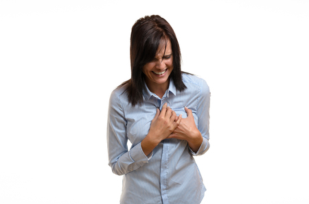 Young woman suffering angina, a myocardial infarct or a heart attack clutching her chest in agonising pain in a healthcare concept, upper body isolated on whiteの写真素材