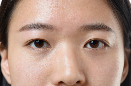 Close up cropped view of the calm dark brown eyes of a young Chinese woman looking directly into the cameraの写真素材