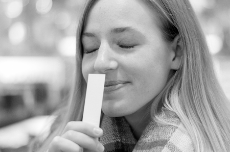 Young blond woman savoring an aroma with a delightful smile of bliss and eyes closed in pleasure as...