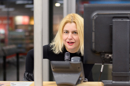 Front portrait of woman dispatcher with blonde hair looking at camera, speaking into microphone, at...