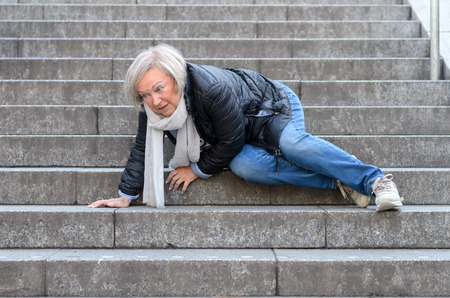 Senior woman accidentaly falling down stone steps outdoorsの写真素材