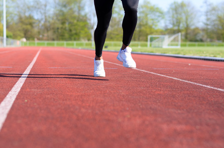 Running muscular legs of a young athlete training or working out on a sports track in a low angle view along the laneの写真素材