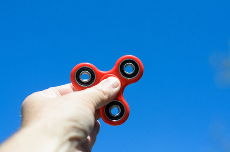 Man playing with a red hand spinner fidget toyの写真素材