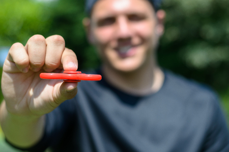 young man playing with a fidget spinner, focus on spinnerの写真素材