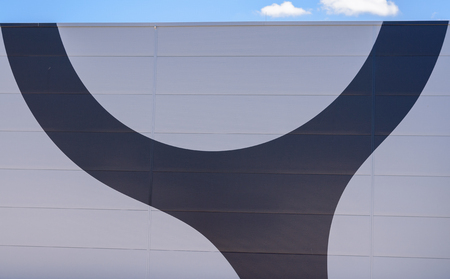 Curved dark grey sign painted on a wooden wall with planks in a close up view