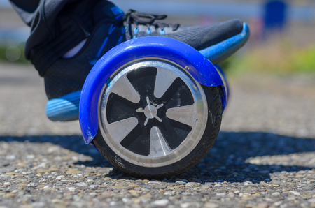 Person riding a hover board in a close up low angle view of the wheel and a foot in a sneakerの写真素材