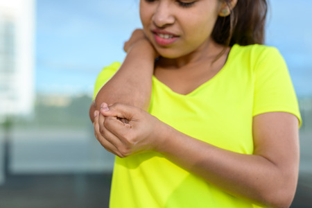 Young woman holding painful elbow during exercising outdoorsの写真素材