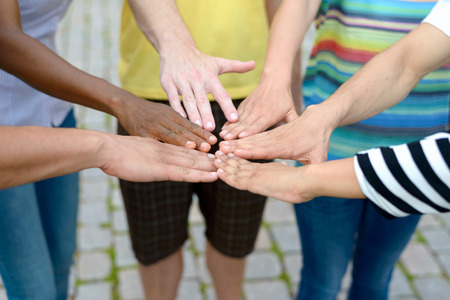 Diverse group of multiethnic people touching hands in a circle in a teamwork or social acceptance...