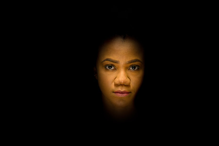 Mysterious night portrait of a pretty young African woman with a serious expression surrounded by...
