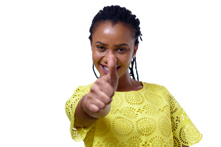 Young smiling African American woman giving thumb up while standing against white backgroundの写真素材