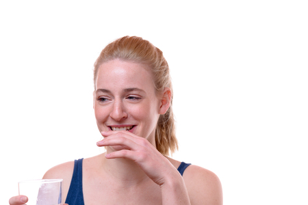 Happy young woman with an amused expression holding her hand to her mouth as she looks to the side...