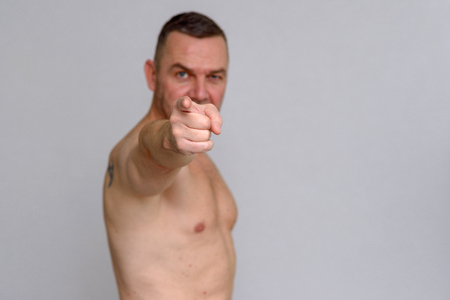 Man pointing to the camera before grey backgroundの写真素材