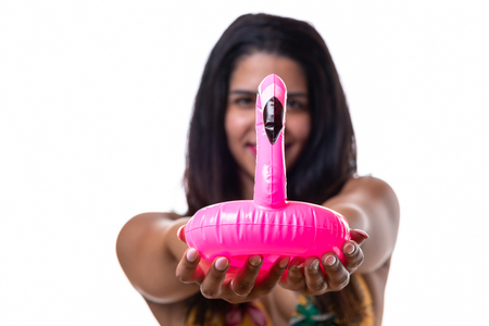 A pretty woman in a bikini holding up a pink, inflatable flamingo in a tropical themed portrait with copy space.の写真素材
