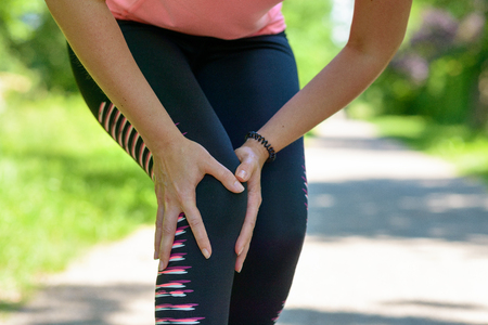 Close up Athletic Woman Holding her Painful Injured Knee While Doing an Outdoor Exercise.の写真素材