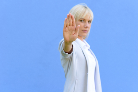 Blond woman giving a halt sign or gesture extending the palm of her hand focus to hand