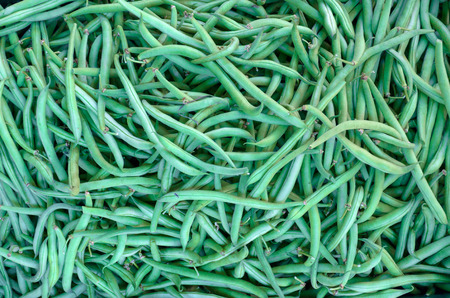 Background texture of fresh healthy green runner beans at a farmers market or on sale in a grocery...