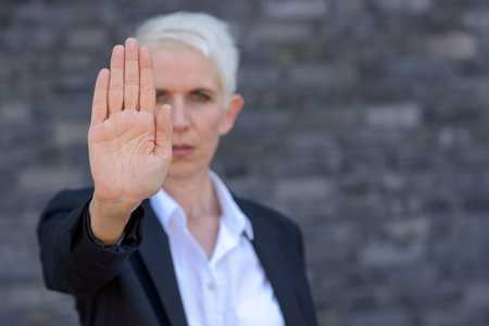 Woman making a stop or halt gesture with her hand in a front view focus on hand