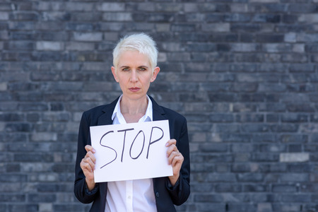 Businesswoman is holding a sign in front of herself with the inscription STOP