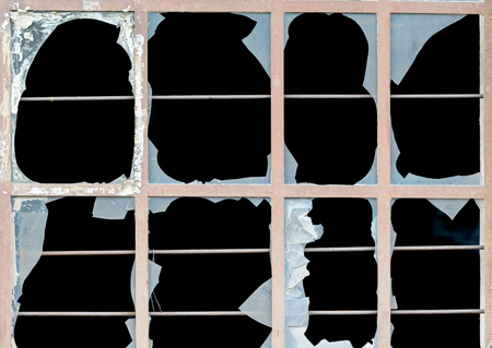 Old window with broken panes of opaque white glass with jagged edges over a dark background