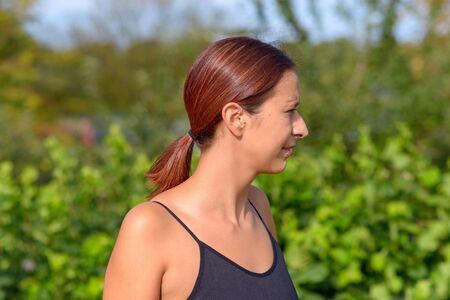 Attractive woman looking aside outdoors in summer sunshine watching something off frame to the rightの写真素材