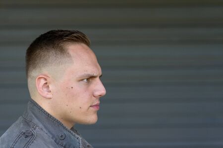 Profile portrait of a trendy attractive young man in his early twenties looking to the right towards...
