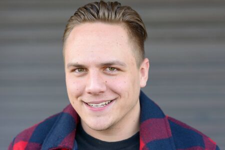 Attractive modern young man in his twenties looking at the camera with a quiet friendly smile in a...