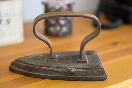 Small vintage metal flat iron for de-wrinkling fabric by heating the metal over a fire in close up...