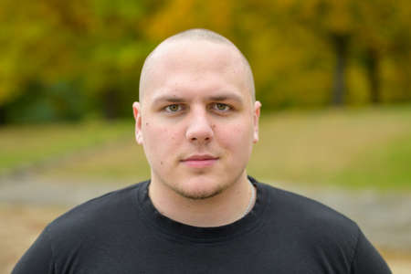 Thoughtful intense serious young man outdoors in a park in autumn