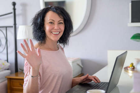 Woman waving with her hand while doing home office