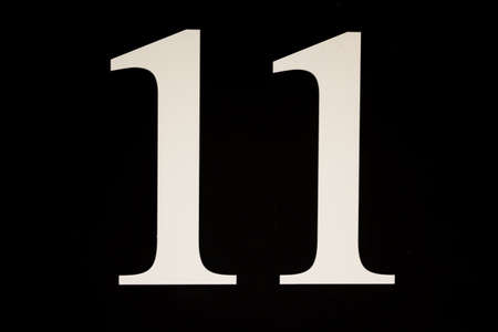 High contrast black and white sign with the stencilled number eleven - 1 - in a close up full frame...
