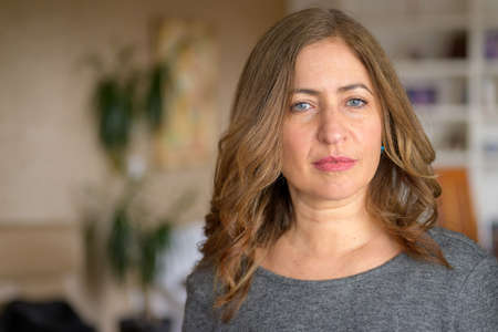 Serious attractive middle-aged woman staring at the camera with an intense thoughtful look indoors...