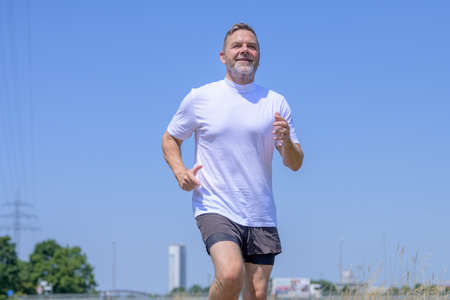 Low angle view of a senior man working out jogging against a clear sunny blue sky with copyspace in...